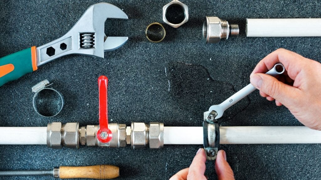 Plumber repairing a pipe valve with an adjustable wrench in St. Petersburg