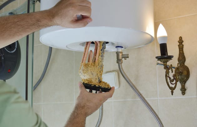 Technician removing mineral buildup from a water heater in St. Petersburg