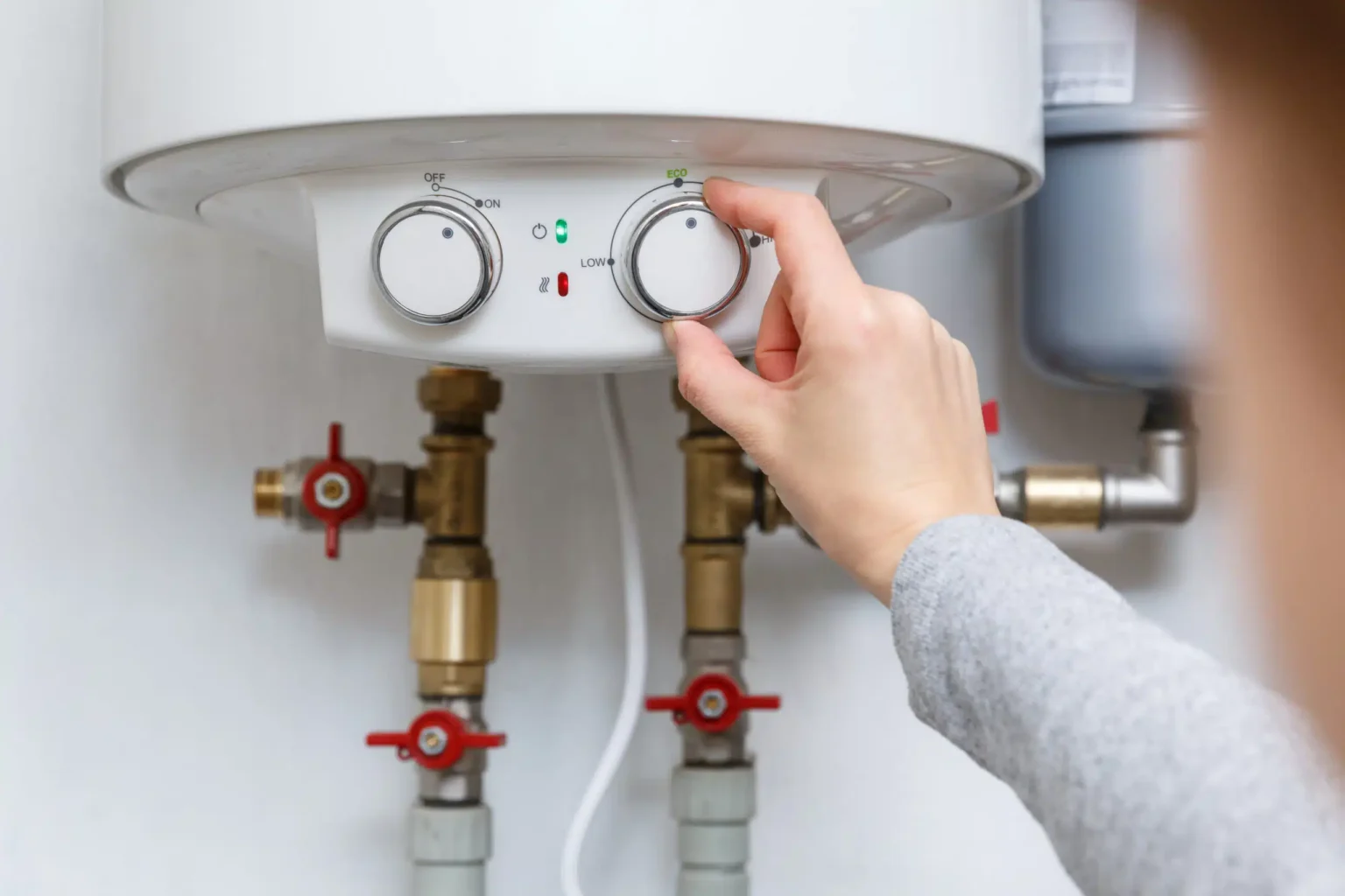 Homeowner adjusting the temperature controls on a water heater in St. Petersburg